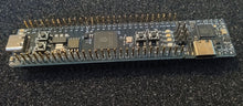 Load image into Gallery viewer, A Proton breadboard-friendly RP2350BA4 dev module with a USB-C port, GPIO pins, and buttons, with a bonus snap-off Debug Probe, resting on a dark textured surface.
